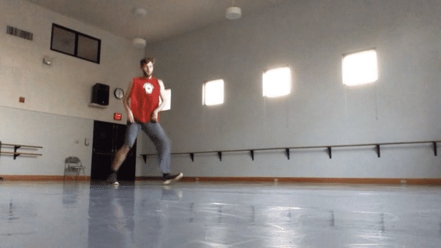 An animated image of instructor Brendan Behan freestyling in a large dance studio. The movement shows fast-moving house dance footwork.