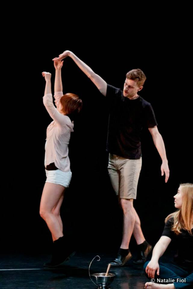 Brendan P. Behan in performance dancing with two women on stage.