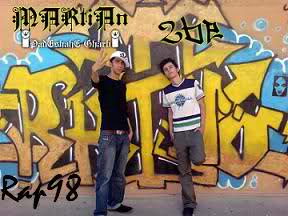 Rappers 2be and Martian pose in front of graffiti on a wall in an image watermarked in the bottom left corner with Rap98, the name of the early websites dedicated to Iranian hip hop